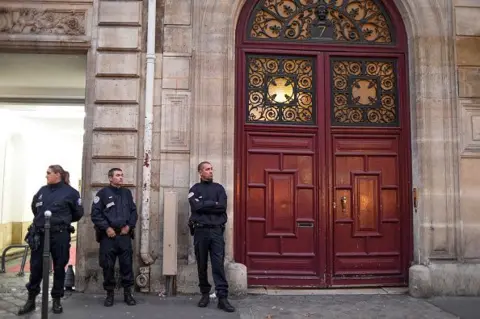 Getty Images Three police officers stand outside a large red door