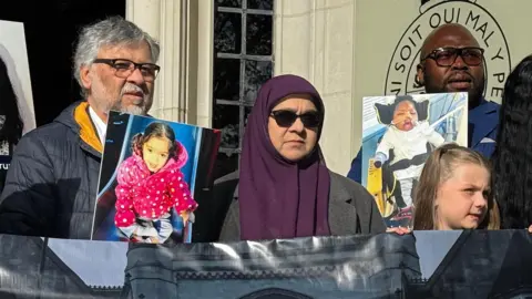 BBC Rashid and Aliya Abbasi (left), the parents of Zainab Abbasi, Lanre Haastrup (L), father of Isaiah Haastrup; outside the Supreme Court in London. They are holding up pictures of their children.