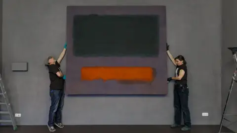 Aad Hoogendoorn/Museum Boijmans Van Beuningen 'Art handlers' from Museum Boijmans Van Beuningen install Rothko's Grey, Orange on Maroon, No.8 (1960), a painting including a large black rectangle and a small orange rectangle on a maroon backdrop, in the Stedelijk Museum Schiedam