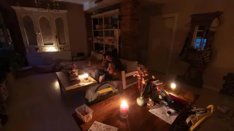 EPA A resident, plays with his pet inside his home lit with candles amid a power outage in Murcia