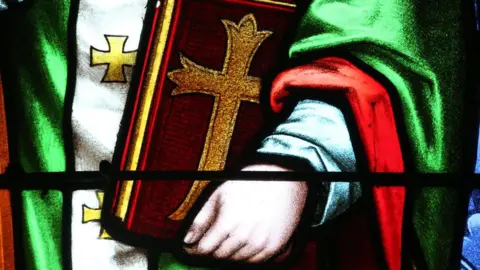 Getty Images A stained glass window depicting St Augustine of Hippo holding a bible. 