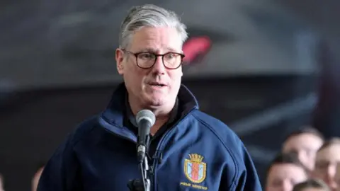 Reuters Sir Keir Starmer wearing a royal blue jacket with a prime minister crest on the chest.