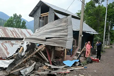 AFP via Getty Images Local residents stand outside their house that was destroyed by Pakistani artillery shelling as they prepare to evacuate at the Lagama village in Uri, about 100kms from Srinagar, on May 9, 2025.