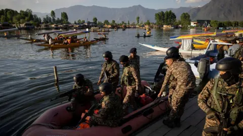 Reuters Indian security force personnel patrol in a boat in the waters of Dal Lake as tourists ride
