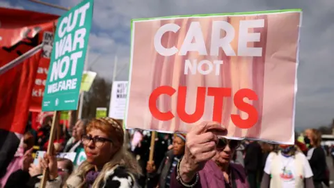 EPA Protesters demonstrate against disability and welfare cuts during the announcement of the Spring Statement outside Parliament in London in March. They hold up placards reading: