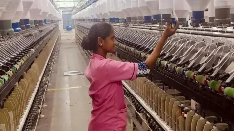 Thirunavkarsu K A woman wearing a pink shirt at a spinning mill factory in the southern Indian state of Tamil Nadu.