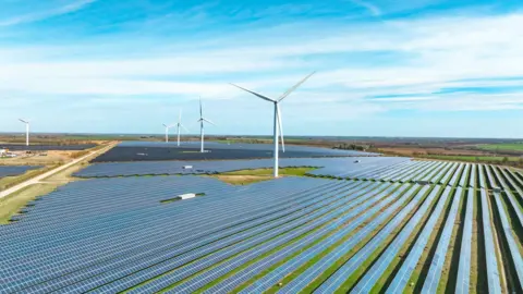 Getty Images Solar panels and wind turbines shown in a landscape