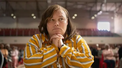 AFP Kelly Smith sits in a courtroom with her hands clasped, wearing a striped shirt.