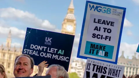 PA Media Creatives in the music industry protest outside UK Parliament. A dark blue placard from trade association UK Music reads: